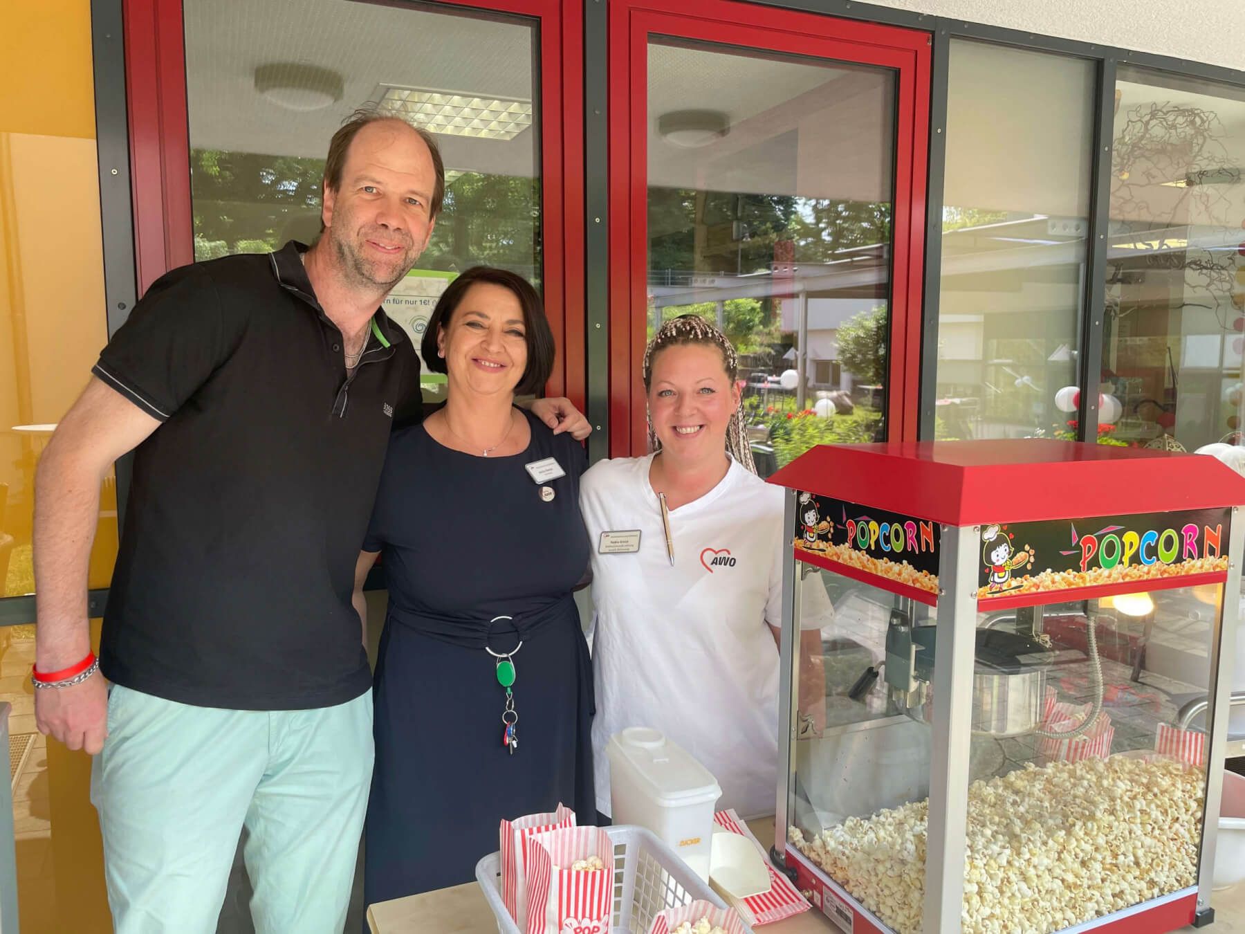 3Mitarbeiter/innen des AWO Seniorenzentrum am Stadtgarten bei der 10-Jahresfeier vor einem Popcornstand