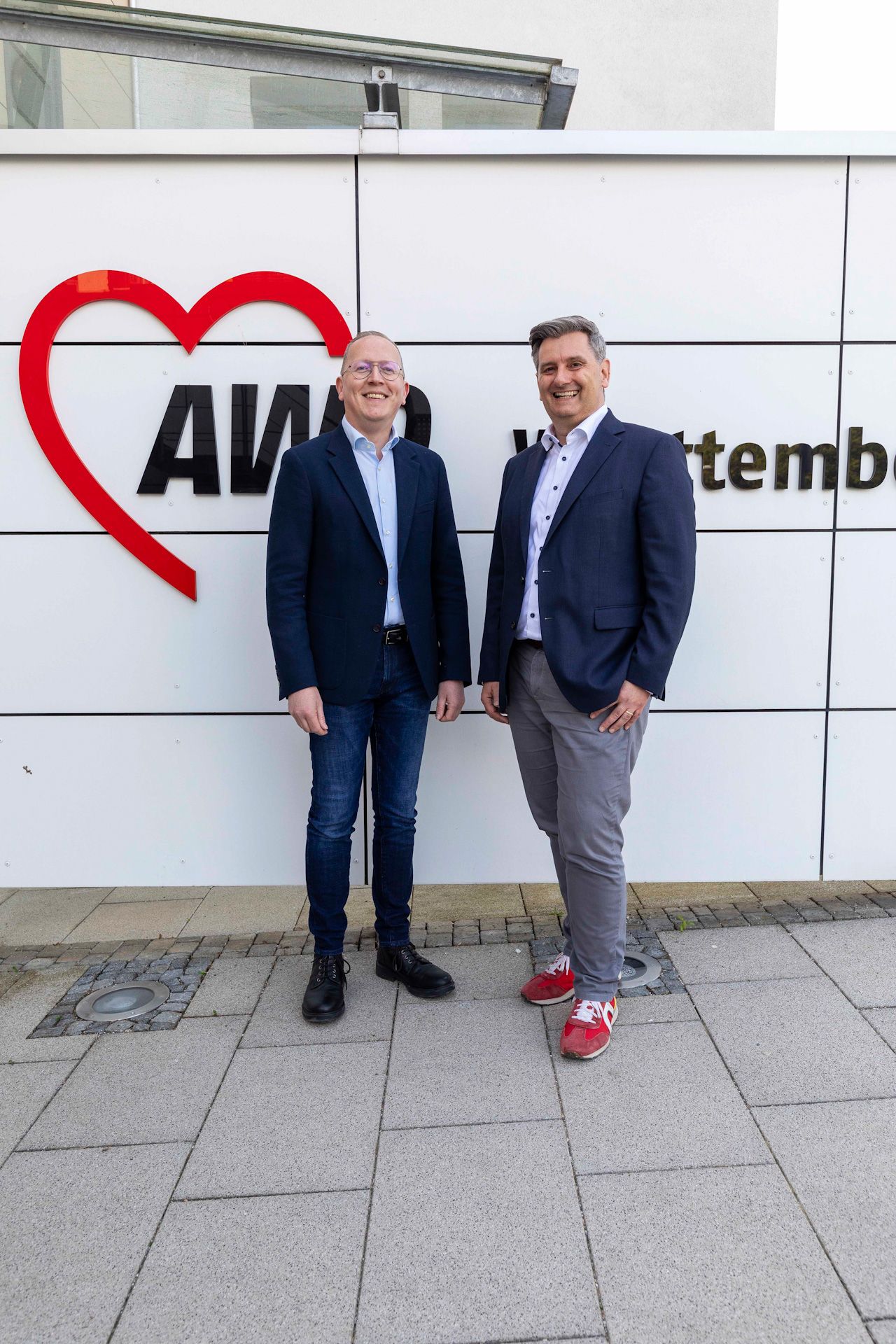 Die Geschäftsführer der AWO-Württenberg vor dem außenlogo des Gebäudes