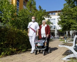 Eine Pflegekraft geht mit einer Bewohnerin spazieren