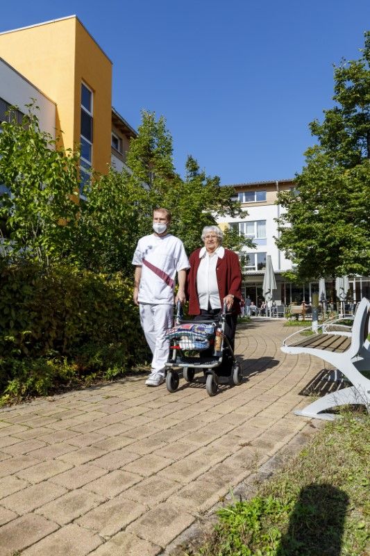 Eine Pflegekraft geht mit einer Bewohnerin spazieren