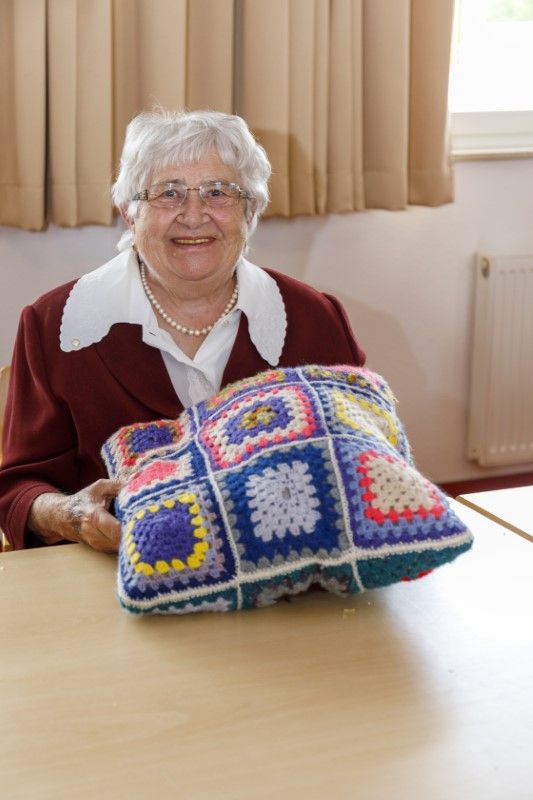 Eine Bewohnerin mit einem gestricktem Kissen