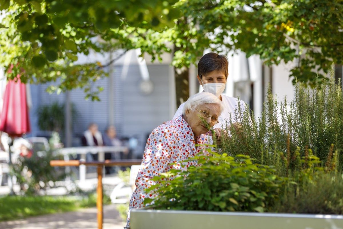 Eine Bewohnerin riecht an den Pflanzen