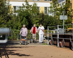 Zwei Bewohnerinnen gehen mit Pfleger spazieren