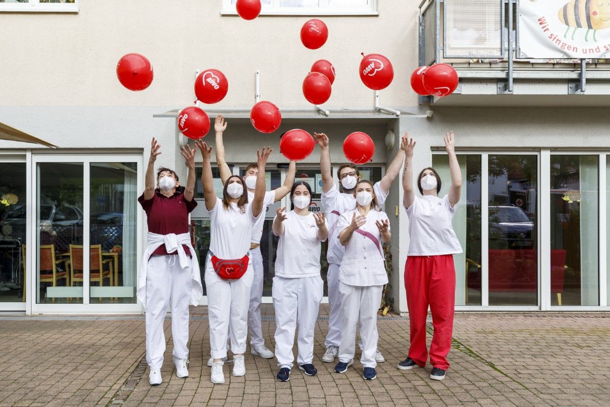 Pfleger*innen werfen Ballons vor dem Eingang in die Luft