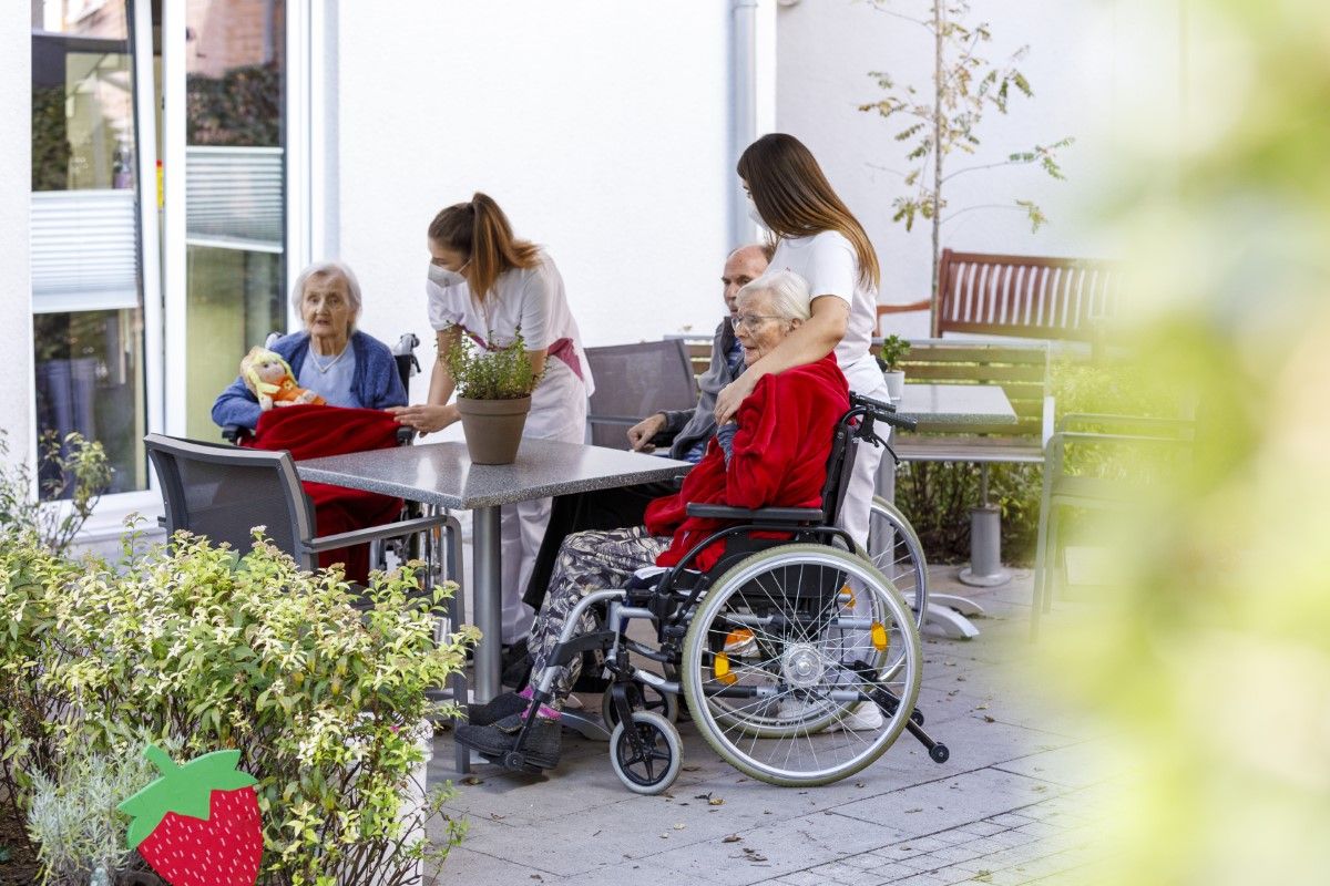 Bewohner*innen sitzen gemeinschaftlich draussen