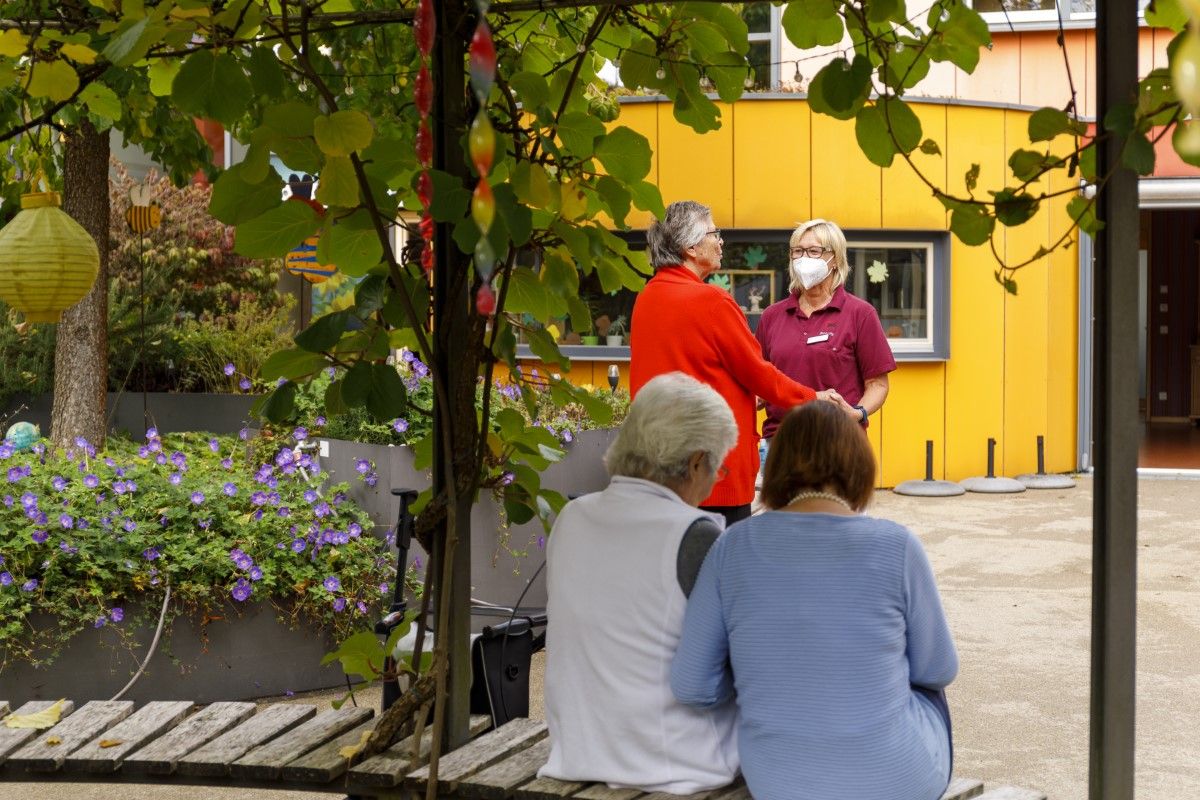 Bewohner*innen sitzen auf einer Bank
